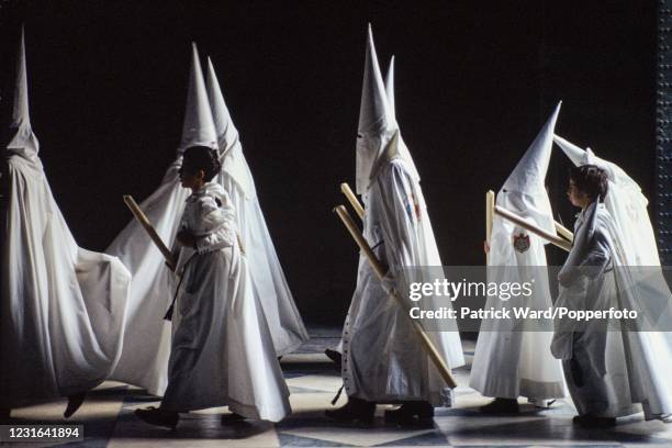Cofradias, members of a religious brotherhood, wearing long white robes and capriotes or conical hats and carrying tall candles entering the...