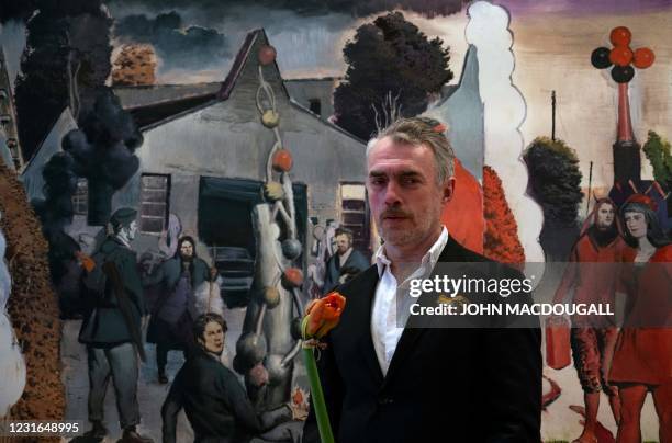 German painter Neo Rauch holds a flower given to him by a wellwisher as he poses in front of his painting "Der Stammbaum", during a press preview of...