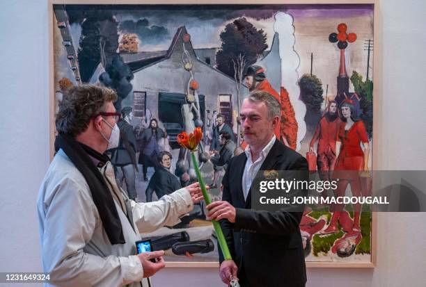 German painter Neo Rauch receives a flower from a wellwisher as he poses in front of his painting "Der Stammbaum", during a press preview of his...