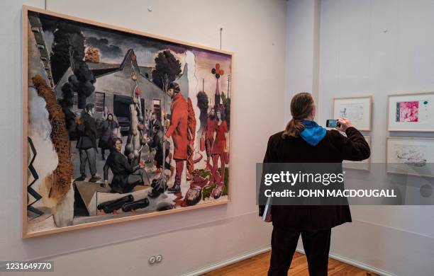 Visitor takes a photo as he stands next to German painter Neo Rauch's painting "Der Stammbaum" during a press preview of his exhibition "Der Beifang"...