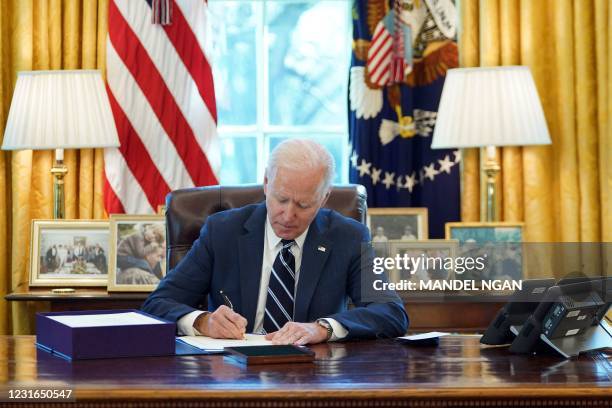 President Joe Biden signs the American Rescue Plan on March 11 in the Oval Office of the White House in Washington, DC. - Biden signed the $1.9...