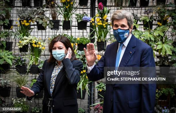 The Mayor of Paris Anne Hidalgo waves as she walks alongside US climate envoy John Kerry prior to their meeting at the Hotel de Ville, in Paris on...
