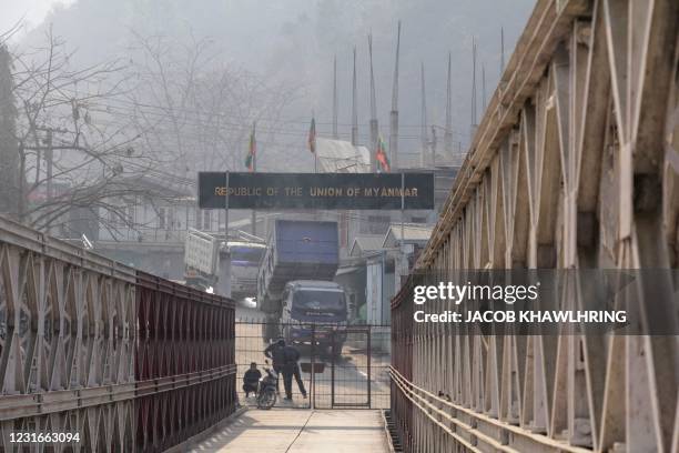 People stand on Myanmar's side of a bridge over the Tiau River, a natural border between India and Myanamar, at Zokhawthar border some 50 Kms from...