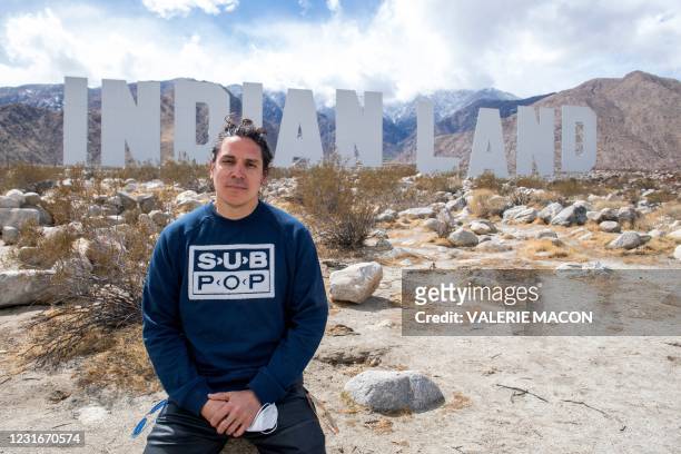 Artist Nicholas Galanin poses in front of his piece, "Never Forget," during the media preview day of the Desert X exhibit, in the Coachella Valley...