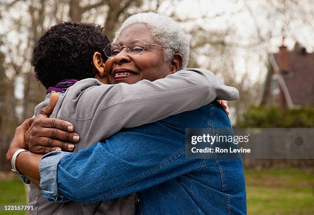 african american senior hugging her daughter - black mom photos et images de collection