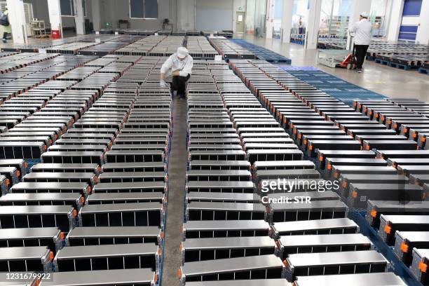 This photo taken on March 12, 2021 shows a worker with car batteries at a factory for Xinwangda Electric Vehicle Battery Co. Ltd, which makes lithium...