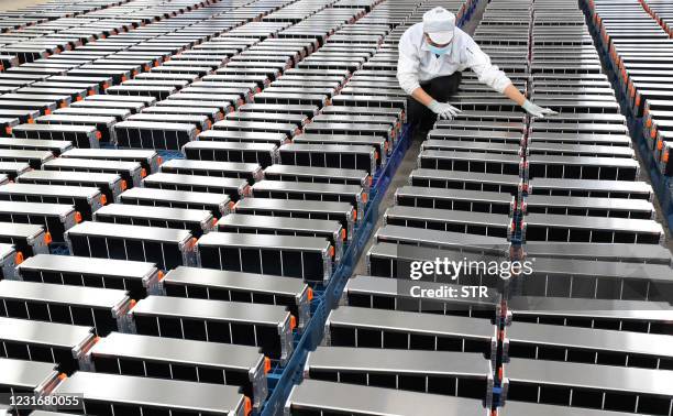 This photo taken on March 12, 2021 shows a worker with car batteries at a factory for Xinwangda Electric Vehicle Battery Co. Ltd, which makes lithium...