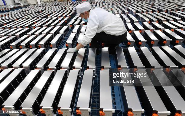 This photo taken on March 12, 2021 shows a worker with car batteries at a factory for Xinwangda Electric Vehicle Battery Co. Ltd, which makes lithium...
