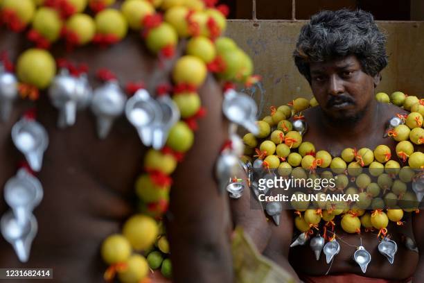 Devotees get their bodies pierced with lemon and 'Paaladai' or a utensil traditionally used to feed milk to infants, wait to take part in a religious...