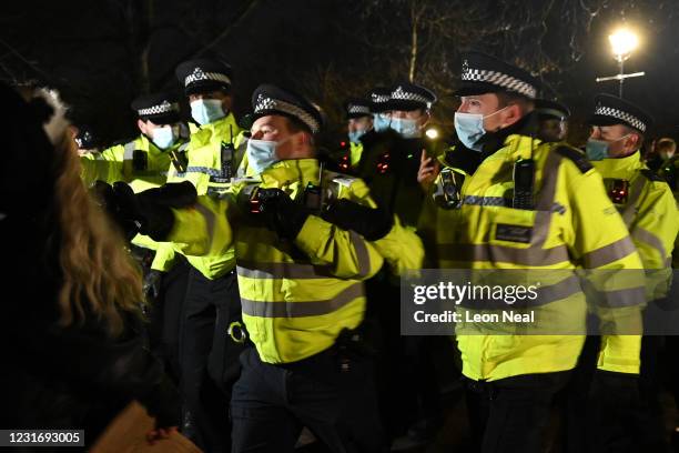 Police Officers arrest a woman during a vigil on Clapham Common, where floral tributes have been placed for Sarah Everard on March 13, 2021 in...