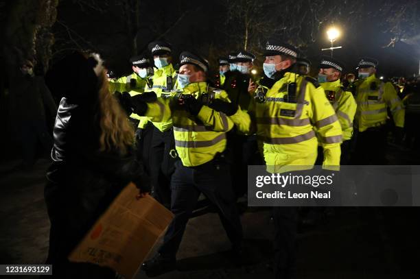 Police Officers arrest a woman during a vigil on Clapham Common, where floral tributes have been placed for Sarah Everard on March 13, 2021 in...