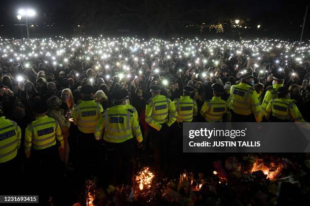 Police officers form a cordon as well-wishers turn on their phone torches as they gather at a band-stand where a planned vigil in honour of alleged...