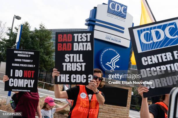 People hold signs at a protest against masks, vaccines, and vaccine passports outside the headquarters of the Centers for Disease Control on March...