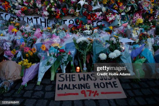 Sign saying "SHE WAS JUST WALKING HOME 97%" is seen among the flowers and candles on Clapham Common where floral tributes have been placed for Sarah...