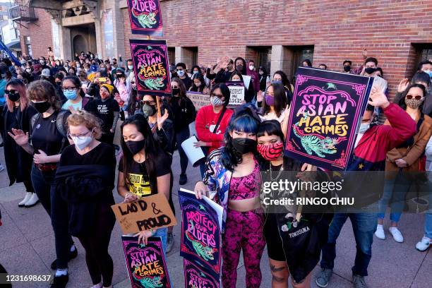 Demonstrators wearing face masks and holding signs take part in a rally "Love Our Communities: Build Collective Power" to raise awareness of...