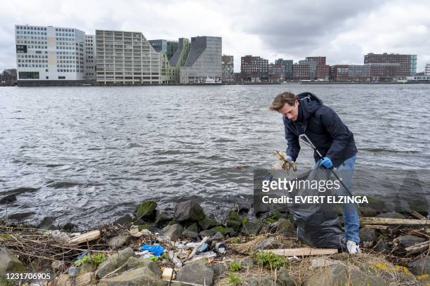 Volt party leader Laurens Dassen cleans up waste from the river IJ during his campaign for the parliamentary elections at EYE Amsterdam, on March 14,...