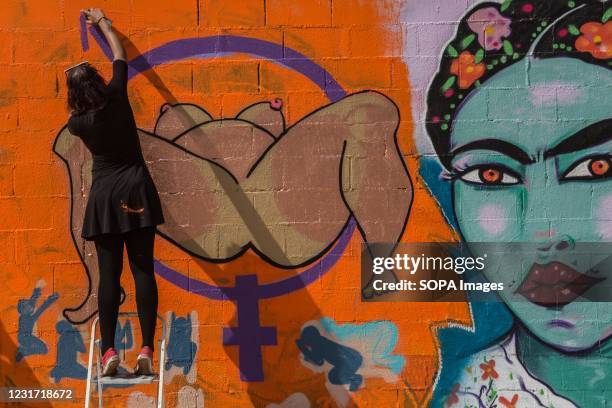 Female demonstrator is seen graffiti writing on the wall during the feminine art day. Latin American feminist collectives have staged a day of...