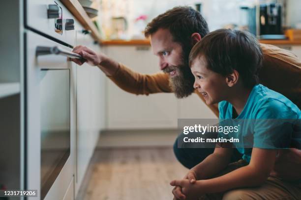 father and son cooking dinner at home - oven stock pictures, royalty-free photos & images