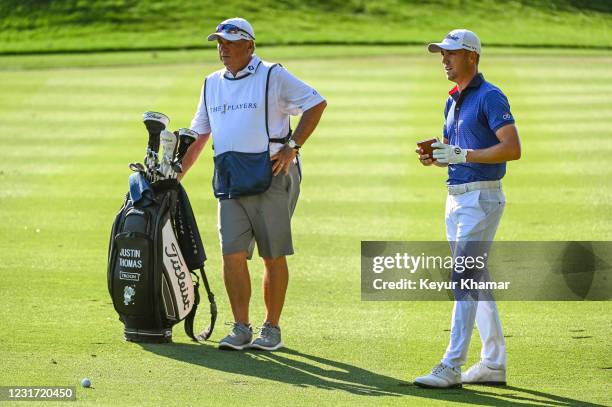 Justin Thomas talks to his caddie Jimmy Johnson and checks his yardage book before playing his approach shot on the 16th hole during the final round...