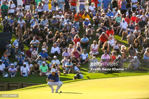 Justin Thomas reads his putt on the 18th hole green as fans watch during the final round of THE PLAYERS Championship on the Stadium Course at TPC...