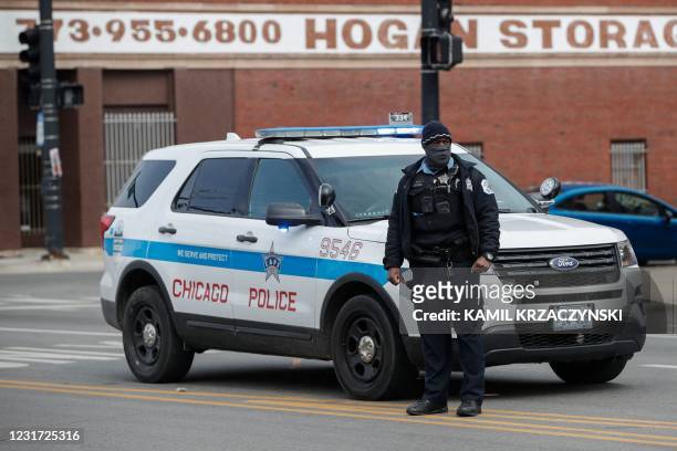 Chicago Police officer monitors the scene after a shooting in Chicago, Illinois, on March 14, 2021. - At least 15 people were shot, two of them...
