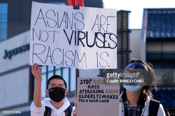 Demonstrators wearing face masks and holding signs take part in a rally "Love Our Communities: Build Collective Power" to raise awareness of...
