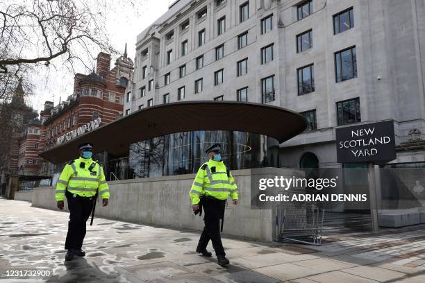 Police officers wearing face coverings due to Covid-19 walk past New Scotland Yard, the headquarters of the Metropolitan Police Service, as...