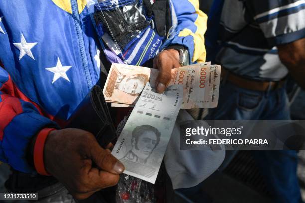 Man displays the new two hundred thousand-Bolivar-note after leaving a bank in Caracas on March 15, 2021. - The Central Bank of Venezuela informed...