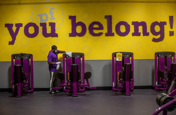 Anthony Carthan, an employee at Planet Fitness on Imperial Highway in Inglewood, disinfects exercise equipment while helping to prepare the fitness...