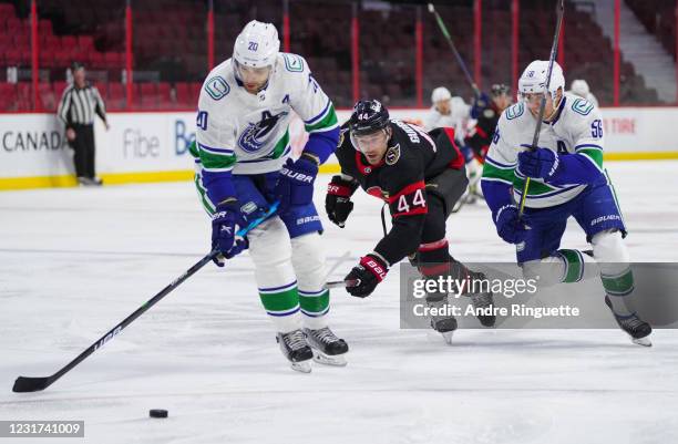 Erik Gudbranson of the Ottawa Senators battles for puck possession against Brandon Sutter and Marc Michaelis of the Vancouver Canucks at Canadian...