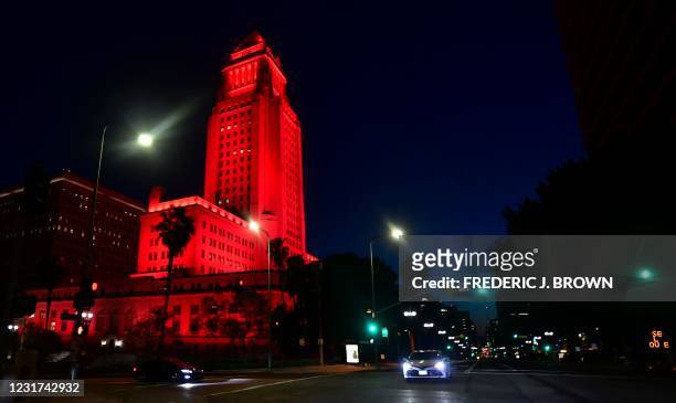 Los Angeles City Hall is lit red on March 15, 2021 on the one-year anniversary of the city's emergency order and the beginning of shutdowns due to...