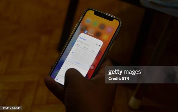 Man uses his mobile phone to check Facebook in Naypyidaw on March 16 as Myanmar authorities ordered telecommunication companies to restrict their...