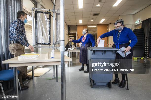 Resident of Staphorstin traditional costume casts her vote in the parliamentary elections on the second day of the vote, on March 16, 2021. -...