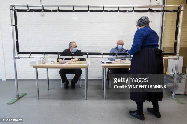 Resident of Staphorstin traditional costume casts her vote in the parliamentary elections on the second day of the vote, on March 16, 2021. -...