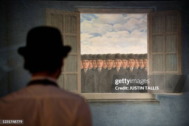 Gallery worker stands alongside an artwork titled 'Le mois des vendanges' by Rene Magritte during a photocall at Christies auction house in central...