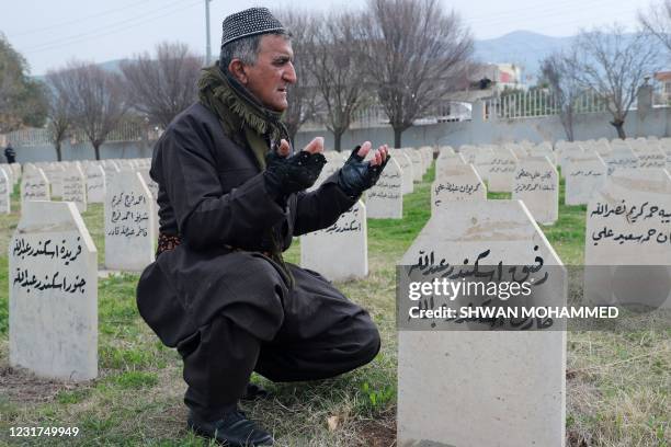 Kurdish man prays over the grave of a relative, killed in the Halabja Chemical attack in 1988, during a march to commemorate the 33rd anniversary of...