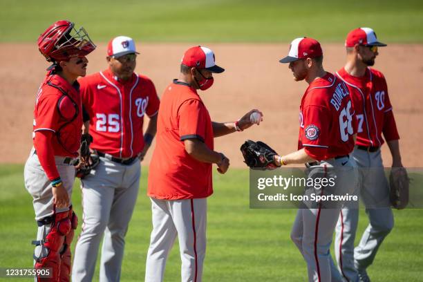 Washington Nationals manager Dave Martinez hands the ball to Washington Nationals non-roster invitee pitcher Bryan Bonnell on the mound along with...