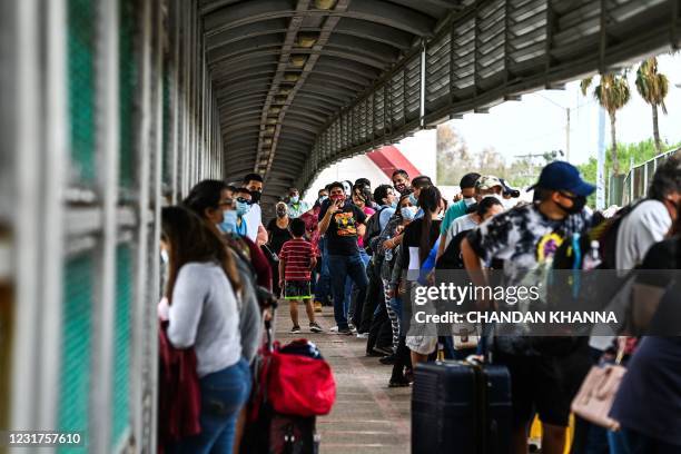 Migrants mostly form Central America wait in line to cross the border at the Gateway International Bridge into the US from Matamoros, Mexico to...