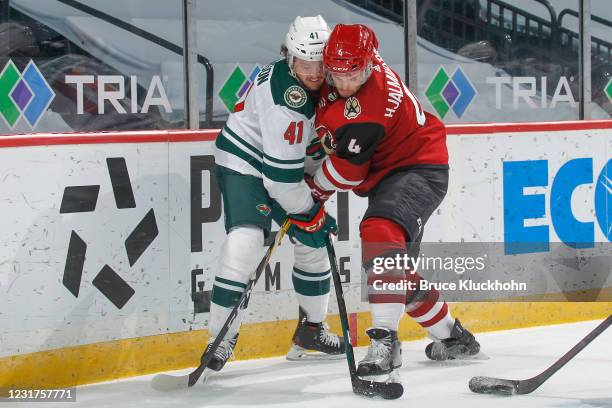 Luke Johnson of the Minnesota Wild and Niklas Hjalmarsson of the Arizona Coyotes battle for the puck along the boards during the game at the Xcel...