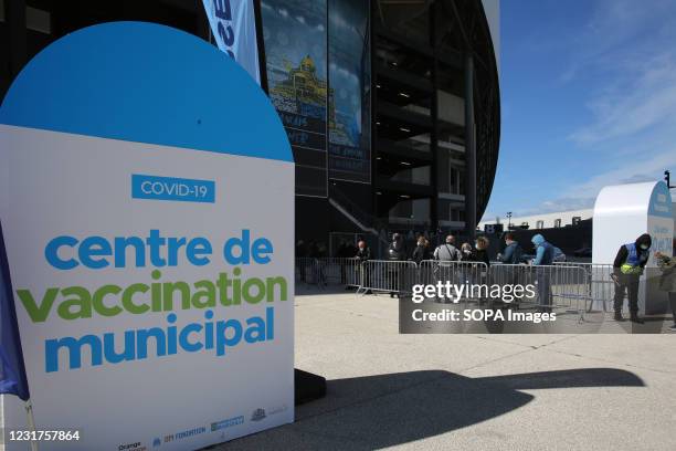 Sign reading "Centre de Vaccination municipal" is seen next to people aged 50 to 74 wait to be vaccinated in the lounges of the football stadium in...