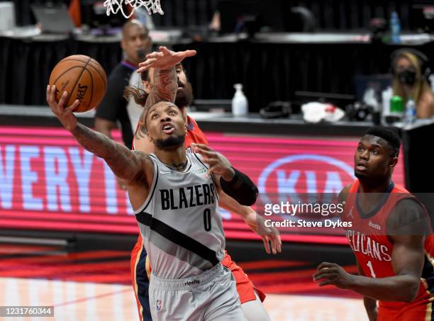 Damian Lillard of the Portland Trail Blazers drives to the basket on Steven Adams of the New Orleans Pelicans as Zion Williamson looks on during the...