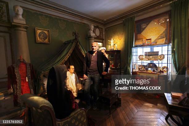 French collector Bruno Ledoux poses with a part of his private collection on Emperor Napoleon I and wax statues representing Napoleon sitting on his...