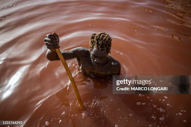 Toure, a Gambian salt harvester, scrapes with his shovel the salt covered crust of the bottom of the Lake Retba in Senegal on March 16, 2021. - Lake...