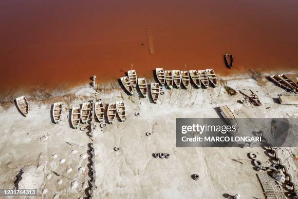 This arial view shows rows of boats used for harvesting salt in Lake Retba in Senegal on March 16, 2021. - Lake Retba, divided from the Atlantic...