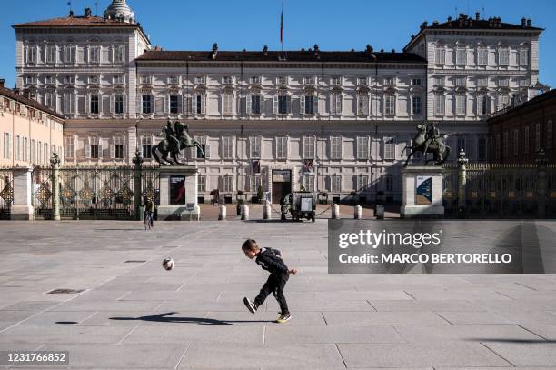 Boy plays with a ball on Piazza Castello on March 17, 2021 in Turin during a new lockdown following new government restrictions over the Covid-19...