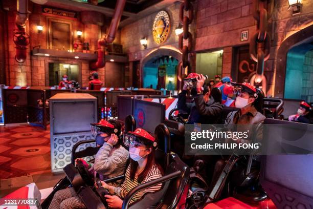 In this picture taken on March 17 fans of Universal Studios Japan wear themed augmented reality goggles for the "Mario Kart" ride during a media...