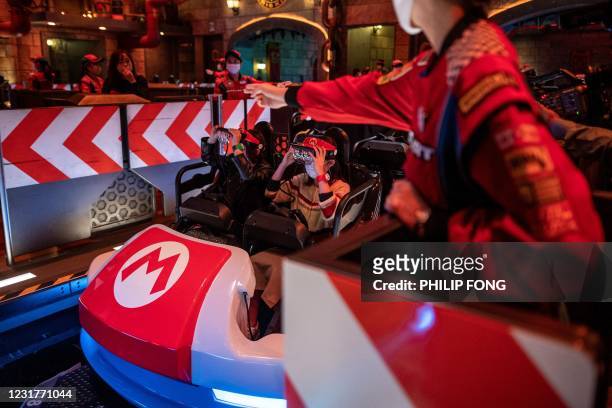 In this picture taken on March 17 fans of Universal Studios Japan wear themed augmented reality goggles for the "Mario Kart" ride during a media...