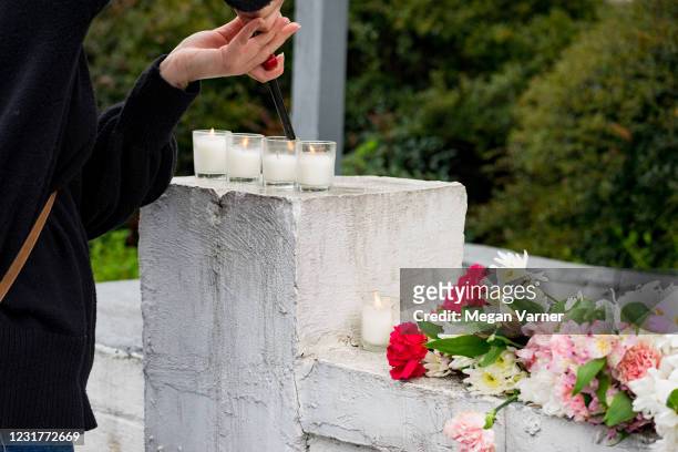 Mourner lights a candle at the site of two shootings at spas across the street from one another, in memorial for the lives lost, on March 17, 2021 in...
