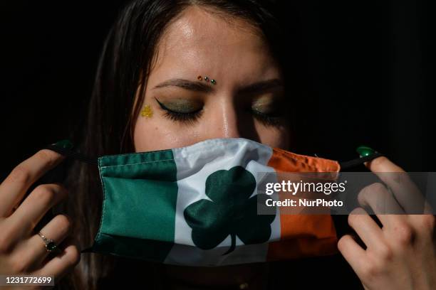 Young woman with fingernails and face decorated for St. Patrick's puts a face mask outside the Irish Potato Cake Company restaurant in Dublin's city...