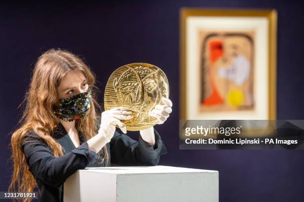 Bonhams employee holds 'Visage de Faune', a a 22-carat gold repouss plate produced by Pablo Picasso and goldsmith Franois Hugo which has an estimate...
